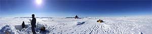 Panorama of 3 people in snow with helicopter