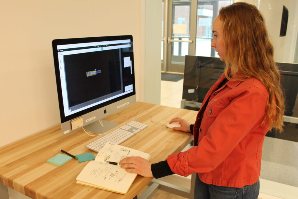 Emma Yount '22 in the working at a standing desk in the Wheaton Fab Lab.