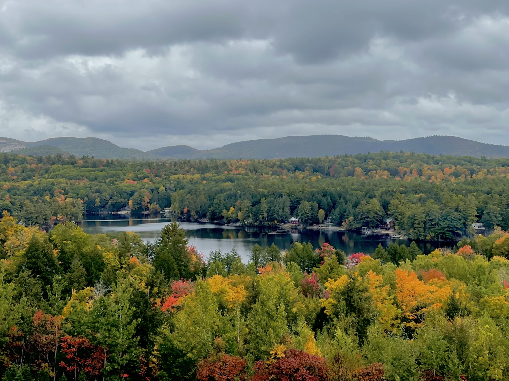 Overview of a large lake in Maine, surrounded by trees. Some trees are starting to get their fall colors