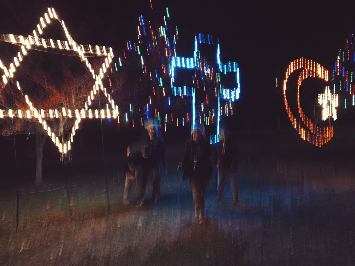 A blurry photo of three friends exploring the religious lighting display at La Salette at night