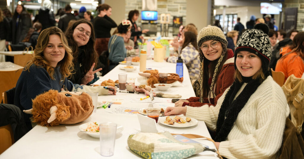 Four students smiling while sitting at a table