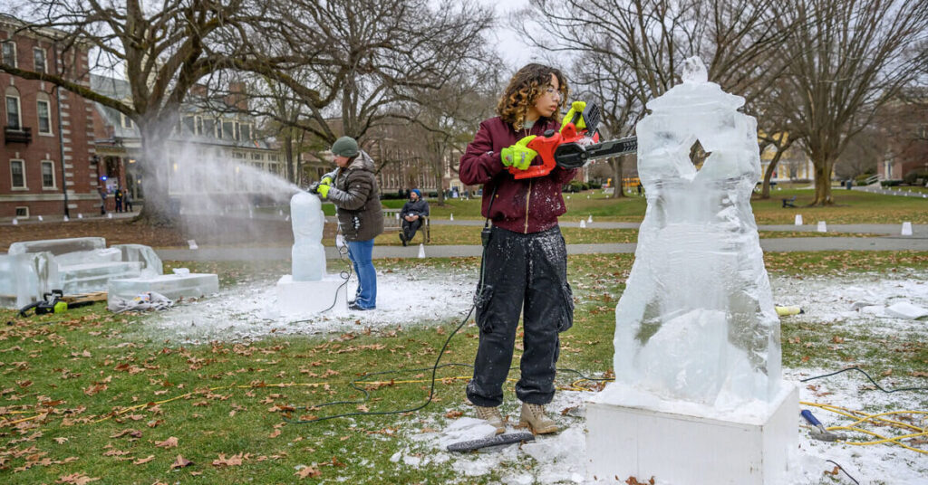 Individuals use chain saws to create ice sculptures