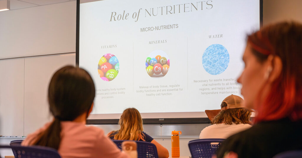 Students view an image on a projector screen, which reads "Role of nutrients."