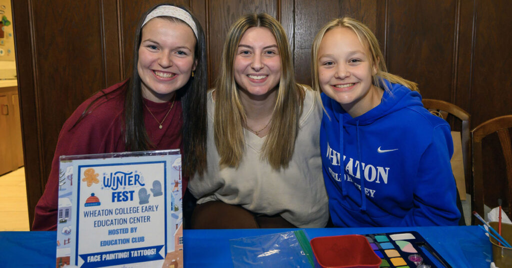 Three smiling young women sit at a table.