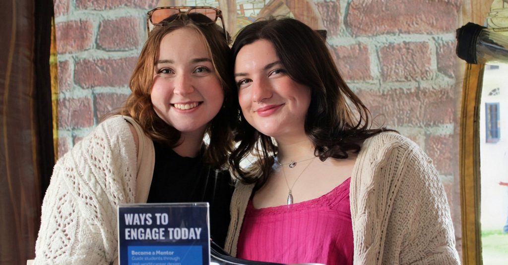 Two young, casually dressed women smile.